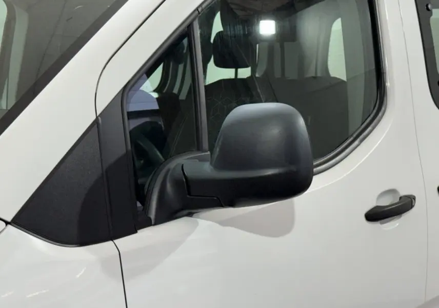 Vue rapprochée du côté gauche d’un Peugeot Rifter blanc 2019, mettant en valeur le rétroviseur noir et la porte avant.