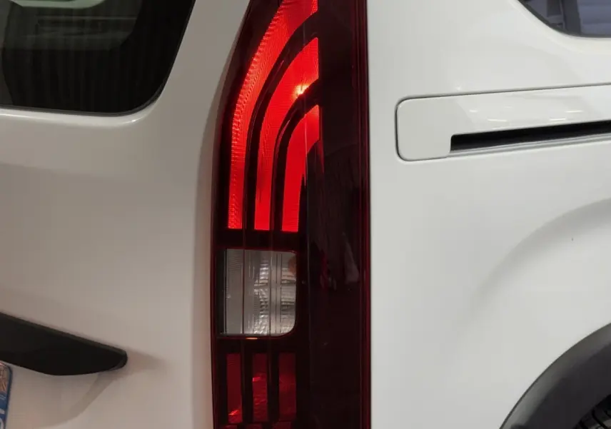 Gros plan sur le feu arrière droit rouge du Peugeot Rifter blanc, avec la portière et la poignée visibles.