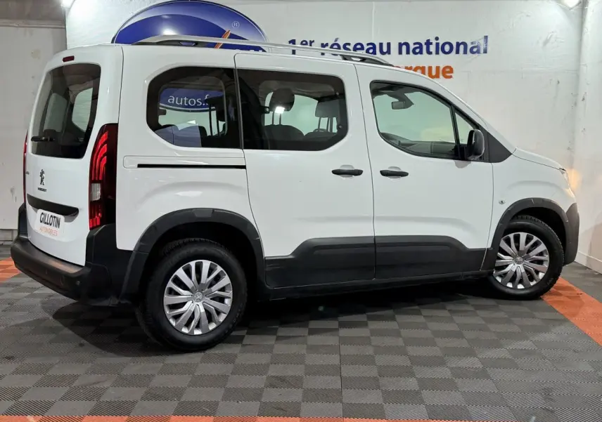 Vue latérale droite d'un Peugeot Rifter blanc 2019 avec rails de toit chromés et protections noires sur bas de caisse.