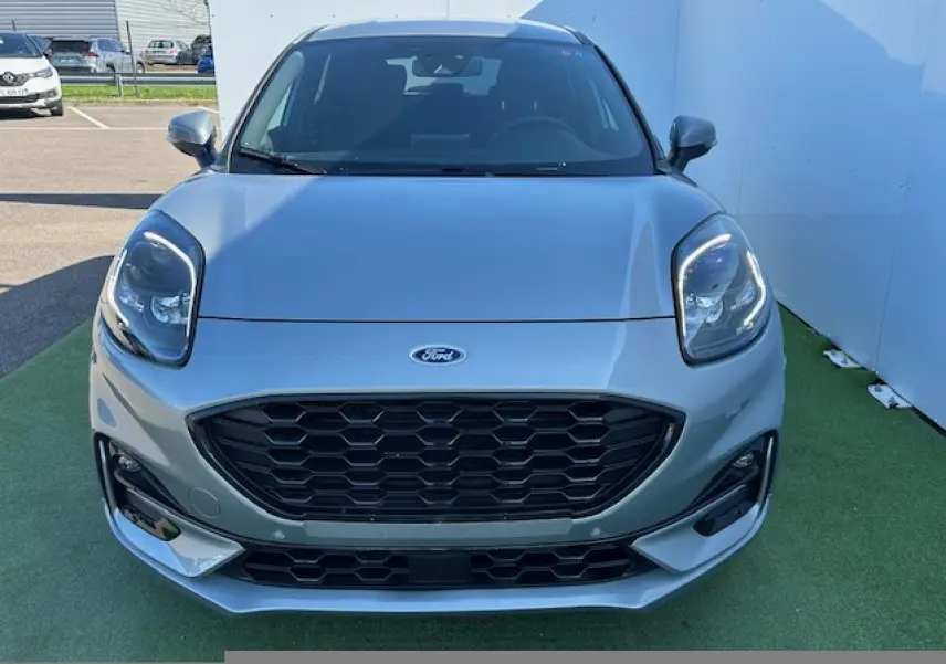 Vue avant d'un Ford Puma gris Solar 2023 avec calandre noire hexagonale et phares LED distinctifs allumés.