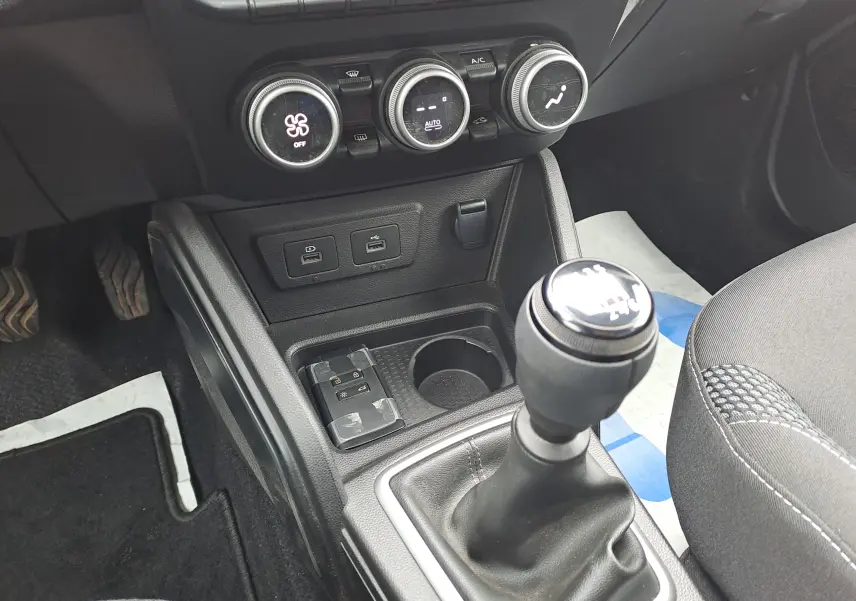 Vue rapprochée de la console centrale du Dacia Duster gris urbain 2024, avec levier de vitesse manuel et commandes de climatisation.