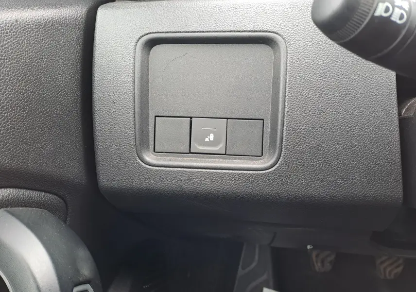 Gros plan sur le tableau de bord côté gauche du Dacia Duster gris urbain 2024, bouton de verrouillage central visible.