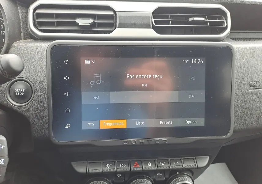Vue rapprochée de l'écran tactile central et des commandes du tableau de bord du Dacia Duster gris urbain 2024.