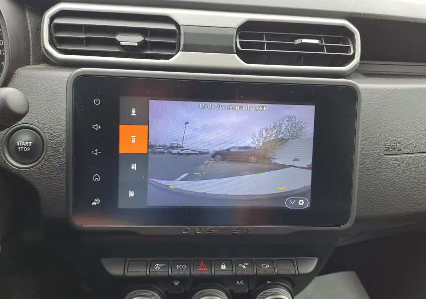 Écran central du Dacia Duster 2024 montrant la caméra de recul avec vue arrière et tableau de bord noir.