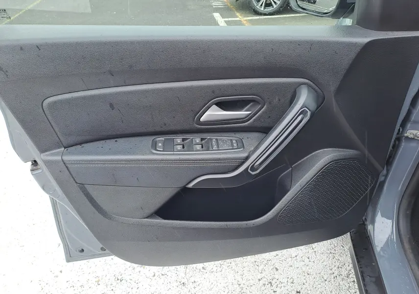 Vue rapprochée de la porte avant gauche gris urbain du Dacia Duster 2024 avec commandes électriques et poignée intégrée.