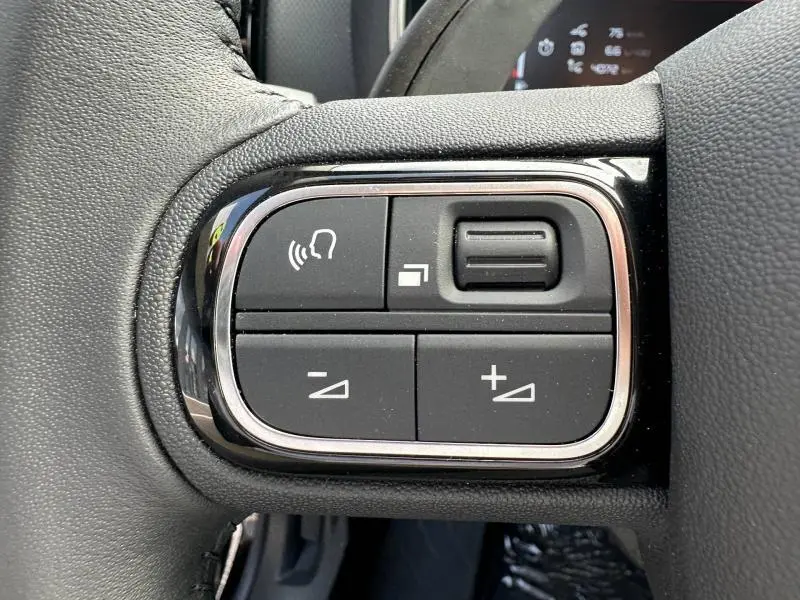 Gros plan sur les commandes de volume et de fonction vocale sur le volant noir du Citroën C5 Aircross 2025.