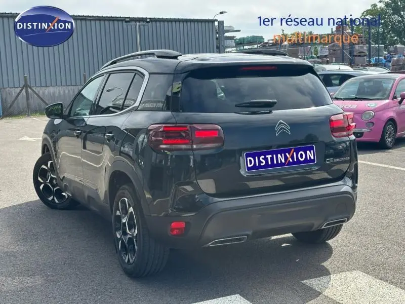 Vue 3/4 arrière droite d'un Citroën C5 Aircross noir Perla Nera 2025 avec feux arrière LED et jantes alliage distinctives.