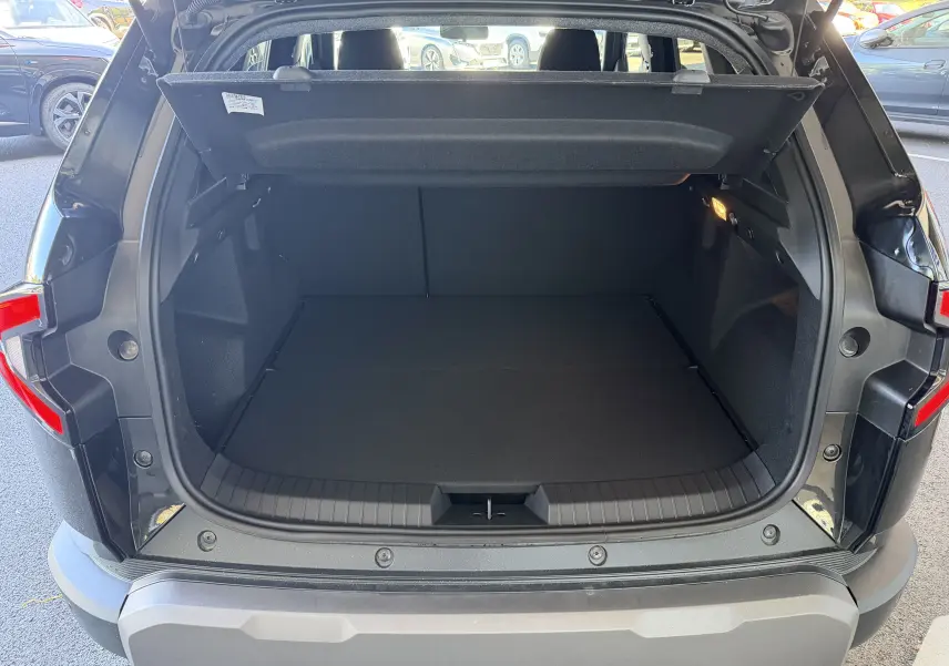 Coffre ouvert vu de l'arrière d'un Dacia Duster Hybrid 155 Journey noir avec hayon levé et intérieur spacieux.