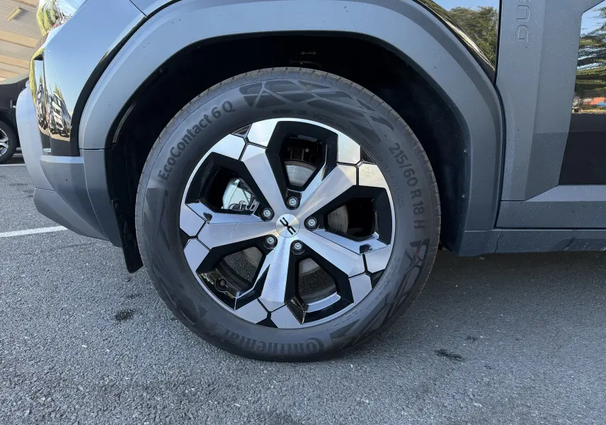 Gros plan sur la roue avant gauche noire du Dacia Duster Hybrid 155 avec jante alliage 18 pouces Tagasan.