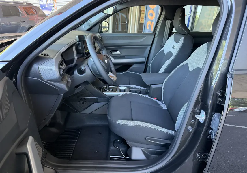 Intérieur du Dacia Duster Hybrid 155 Journey 2026 noir, vue côté gauche montrant les sièges bicolores et le tableau de bord moderne.