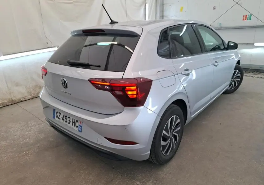 Vue 3/4 arrière droite d'une Volkswagen Polo gris clair avec vitres arrière surteintées et jantes alliage.