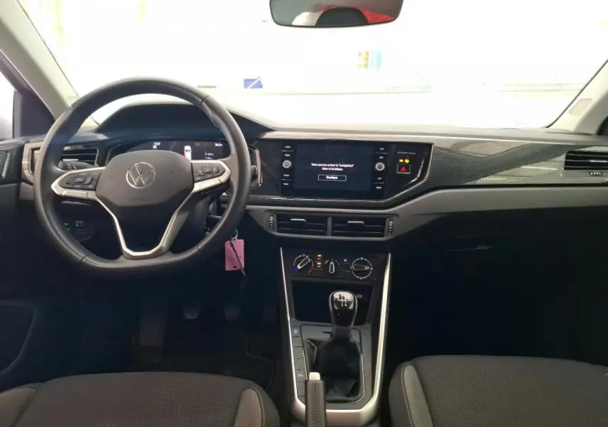 Vue intérieure avant de la Volkswagen Polo gris clair 2024, volant cuir multifonction et levier de vitesses manuel.