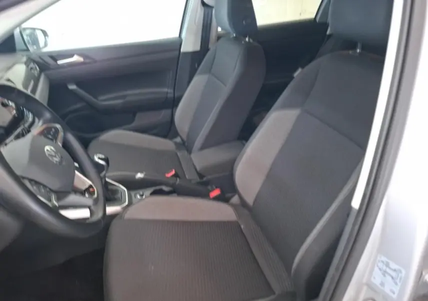 Vue intérieure côté conducteur de la Volkswagen Polo 2024, sièges tissu gris foncé avec accoudoir central.