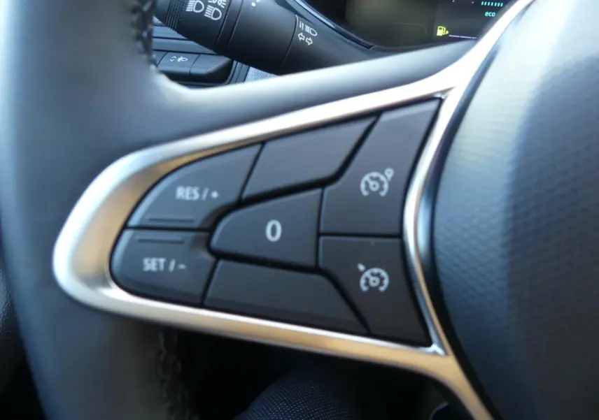 Gros plan sur les commandes de régulateur de vitesse du volant noir de la Renault Clio 1.5 Blue dCi gris schiste.
