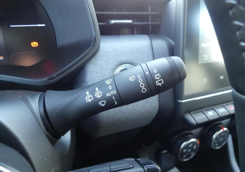 Gros plan sur la commande d'essuie-glace à gauche du volant dans l'habitacle gris et noir de la Renault Clio 2025.