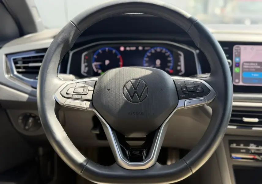 Vue rapprochée du volant cuir multifonctions noir du Volkswagen Taigo TSI 116 DSG R-Line avec tableau de bord digital.