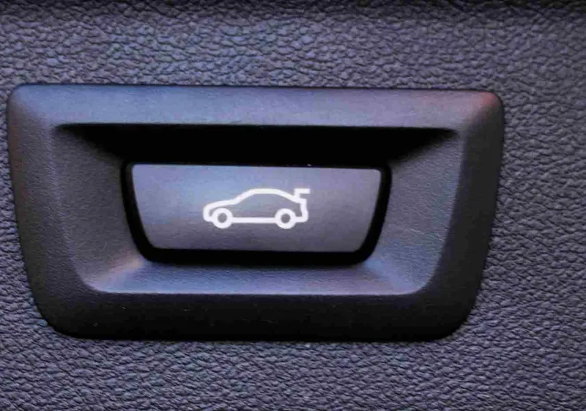 Bouton intérieur noir avec symbole blanc de voiture hybride pour ouverture du coffre du BMW X3 xDrive bleu métal 2023.