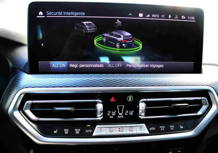 Écran central du BMW X3 xDrive 30e 2023 montrant les réglages de sécurité intelligente et la climatisation digitale.