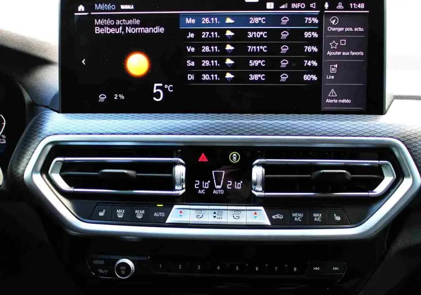 Écran tactile central affichant la météo dans l'habitacle du BMW X3 xDrive bleu métal, version hybride rechargeable 2023.