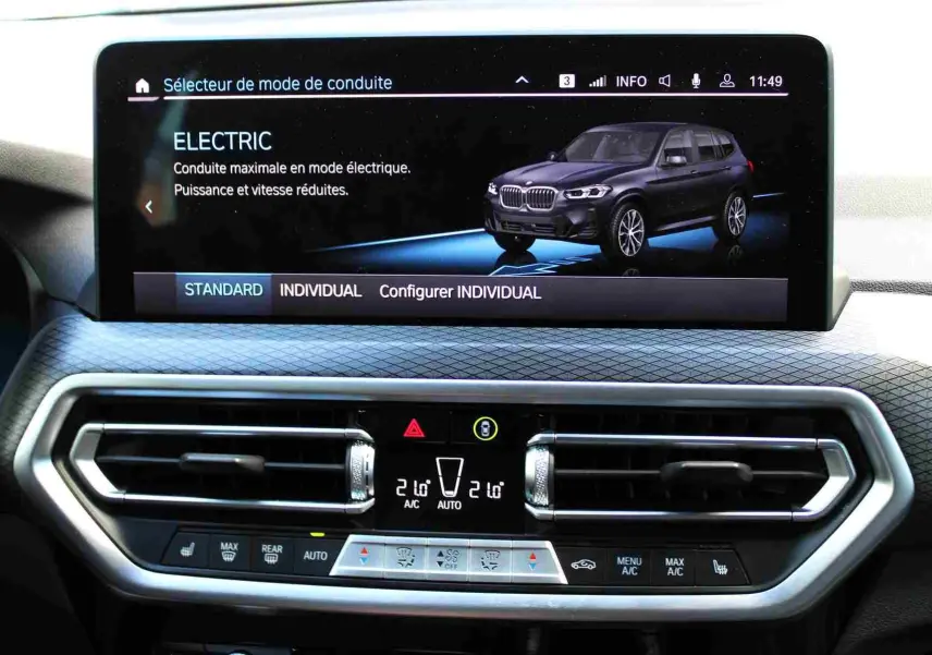 Écran central du BMW X3 xDrive 30e 2023 montrant le mode électrique avec vue 3/4 avant bleu métal du SUV hybride.