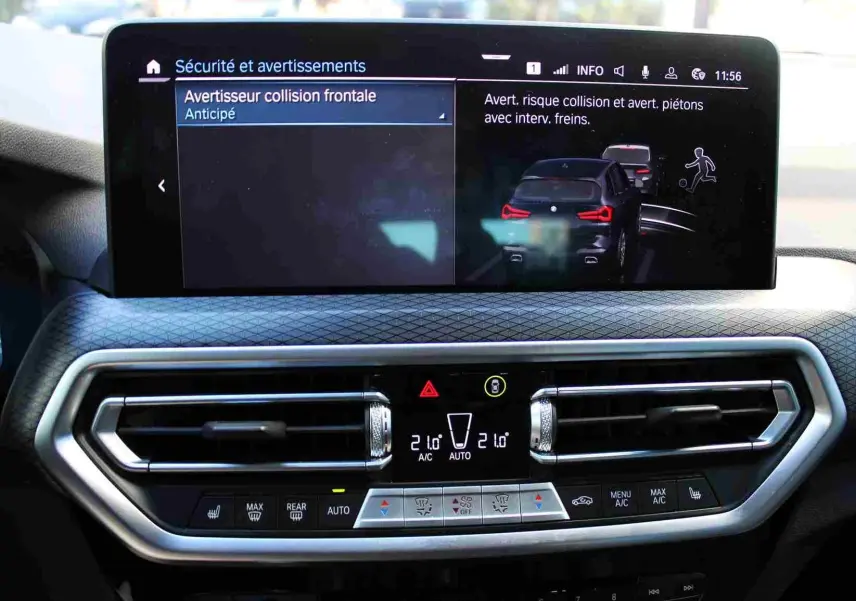 Tableau de bord du BMW X3 xDrive 30e 2023 avec écran tactile affichant l'alerte collision et commandes climatisation intégrées.