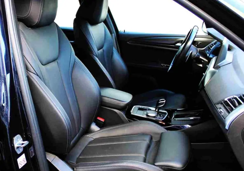 Intérieur côté conducteur du BMW X3 xDrive 30e 2023 avec sièges cuir noirs et console centrale moderne.