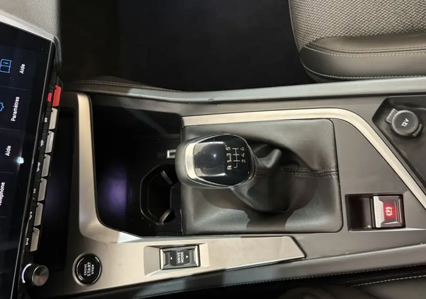 Vue rapprochée de la console centrale de la Peugeot 308 bleu, avec levier de vitesse manuel et bouton démarrage.
