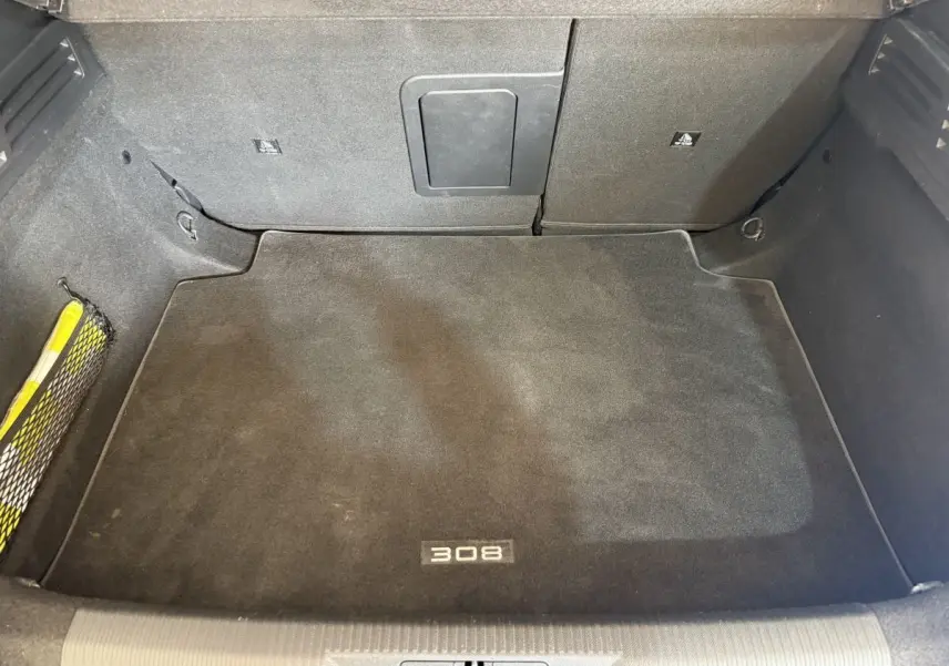 Coffre spacieux vu de dessus, tapis noir avec logo 308, intérieur de Peugeot 308 PureTech 2023.