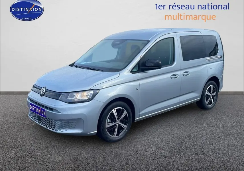 Volkswagen Caddy gris argent vu en 3/4 avant droit, avec jantes alliage et vitres arrière teintées.