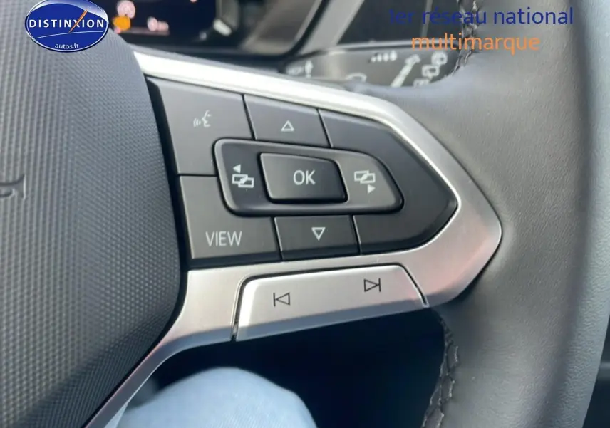 Gros plan sur les commandes multifonctions en cuir du volant côté gauche du Volkswagen Caddy gris argent 2025.