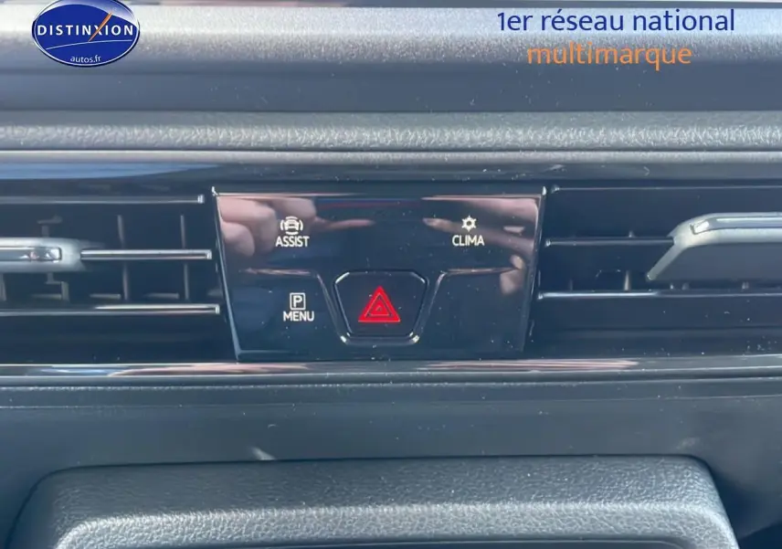 Gros plan sur la console centrale noire du Volkswagen Caddy gris argent, avec boutons d'assistance et climatisation visibles.