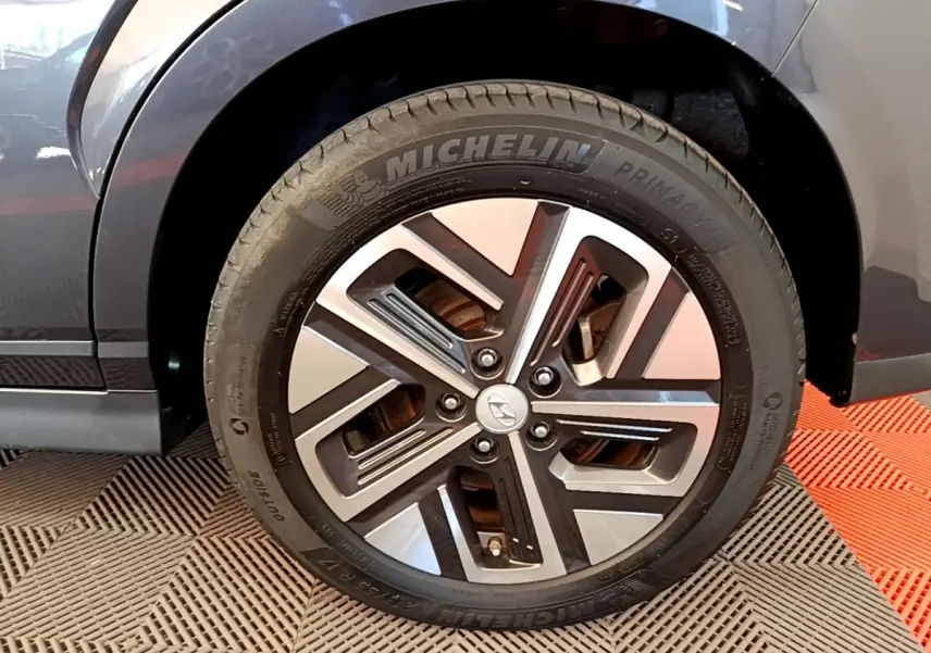 Gros plan sur la roue avant droite grise d'un Hyundai Kona électrique avec jante alliage bicolore et pneu Michelin.