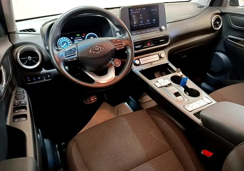 Vue intérieure avant du Hyundai Kona électrique 2021, volant cuir multifonctions et écran tactile central visible.