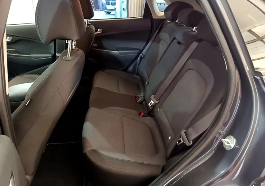 Vue intérieure côté droit sur la banquette arrière noire du Hyundai Kona électrique 2021 avec portes ouvertes.