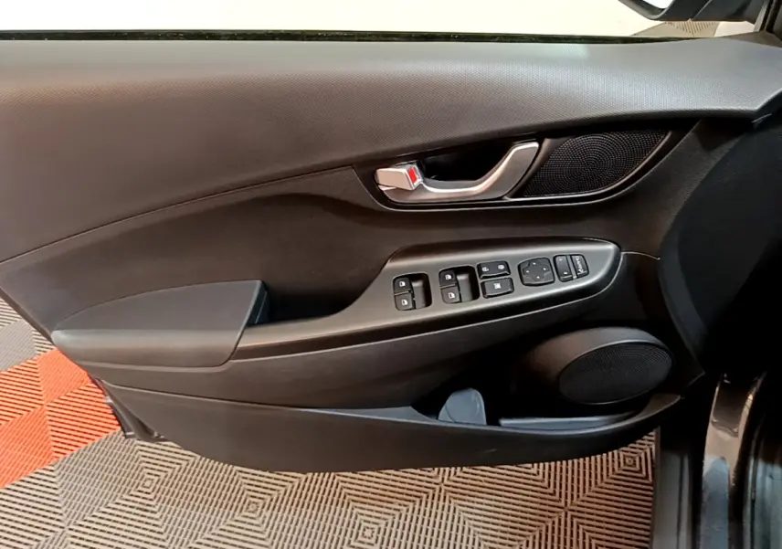 Vue intérieure du panneau de porte côté conducteur noir avec commandes électriques et haut-parleur intégré sur Hyundai Kona électrique 2021.