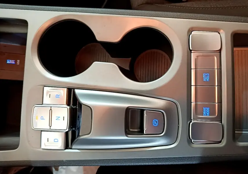 Vue rapprochée de la console centrale grise du Hyundai Kona électrique 2021 avec sélecteur de vitesses boutons et commandes éclairées.