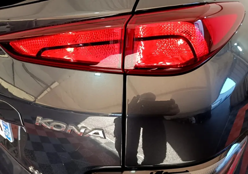 Gros plan sur le feu arrière droit rouge et la carrosserie gris foncé d’une Hyundai KONA électrique 2021.
