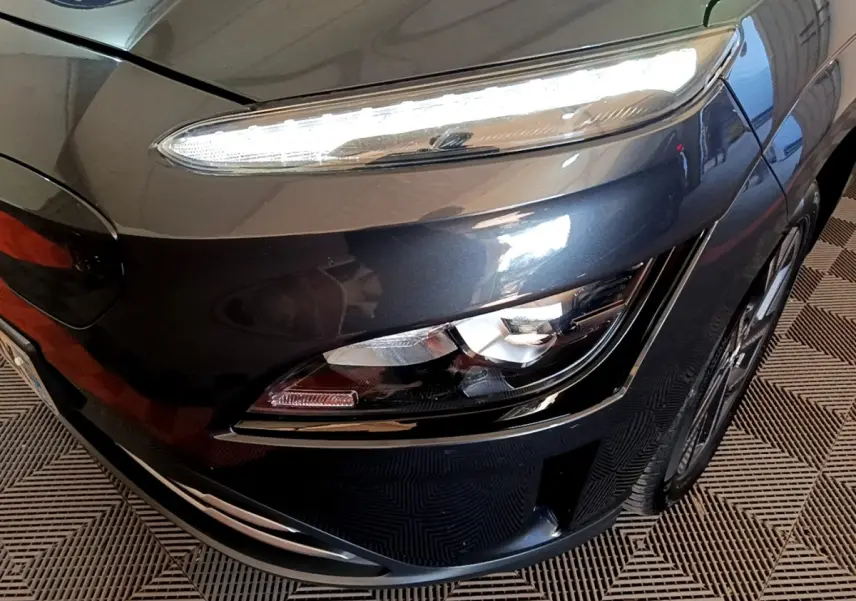 Gros plan sur l'avant droit gris foncé du Hyundai Kona électrique 2021, mettant en valeur ses phares LED distinctifs.