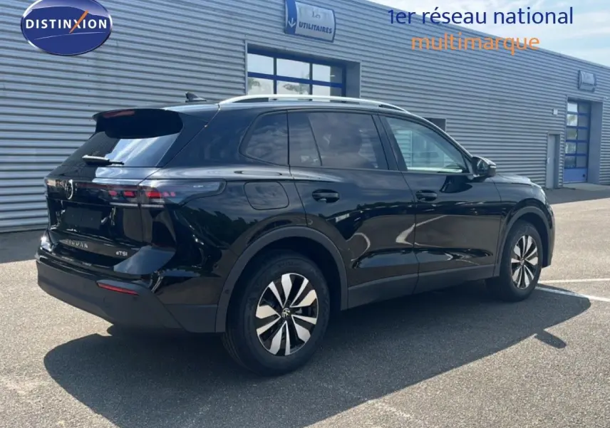 Vue 3/4 arrière droite d’un Volkswagen Tiguan noir Grenadilla métallisé avec jantes bicolores et toit argenté.