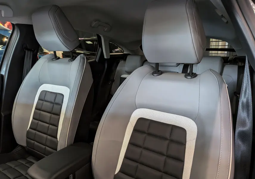 Vue rapprochée des sièges avant en cuir noir et gris clair de la Citroën C4 Hybride 2025, intérieur élégant.