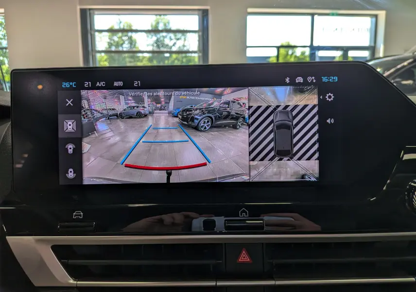 Écran multimédia de la Citroën C4 Hybride 2025 montrant la caméra de recul avec vue arrière et top-down en intérieur showroom.