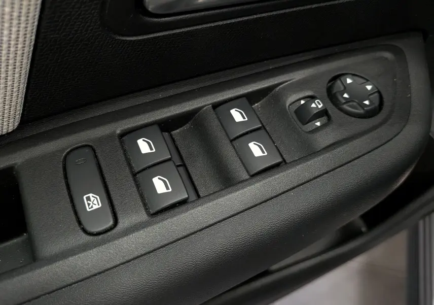 Gros plan sur les commandes de lève-vitres et réglages des rétroviseurs côté conducteur d'une Citroën C4 Hybride gris Mercury.