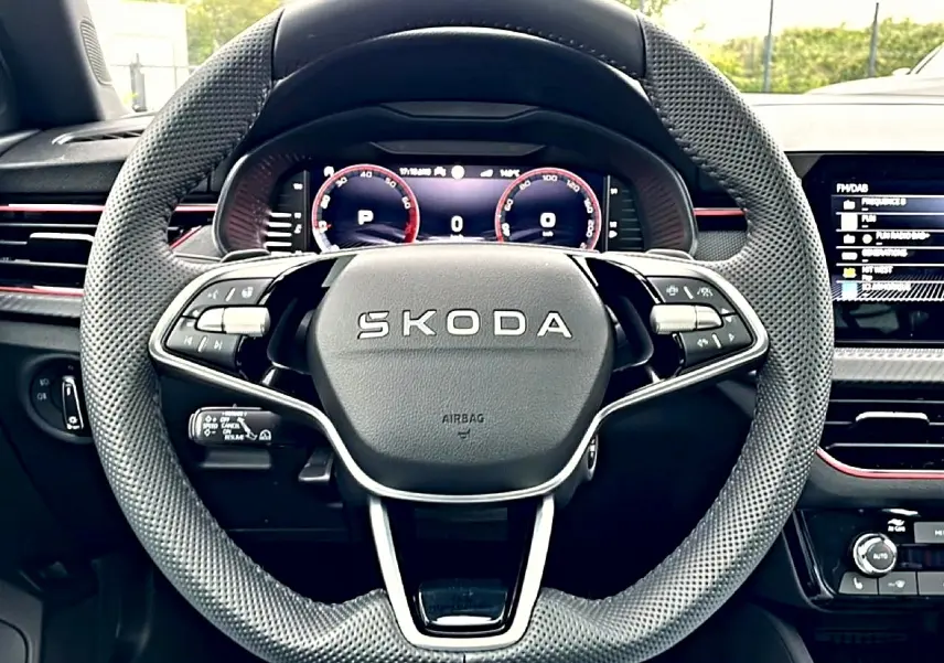 Vue rapprochée du volant sport en cuir perforé noir du Skoda Kamiq 2026 avec tableau de bord numérique et inserts rouges.