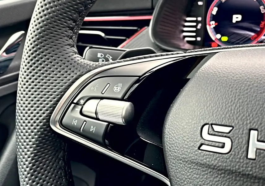Gros plan sur les commandes gauche du volant cuir perforé du Skoda Kamiq blanc nacré, avec molette et boutons multifonctions.