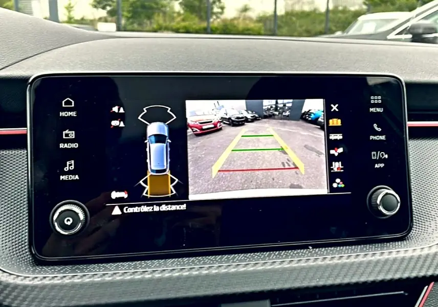 Écran tactile intérieur du Skoda Kamiq blanc nacre montrant la caméra de recul et l’aide au stationnement.