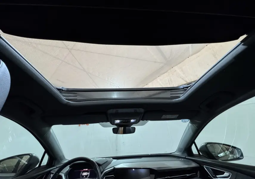 Vue intérieure avant du toit ouvrant panoramique et tableau de bord noir de l’Audi Q4 E-TRON Design Luxe 2022