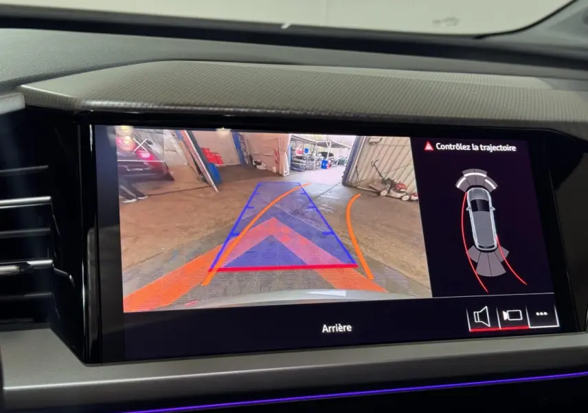 Écran tactile central de l’Audi Q4 E-TRON gris foncé montrant la caméra de recul avec guidage et alertes de trajectoire.