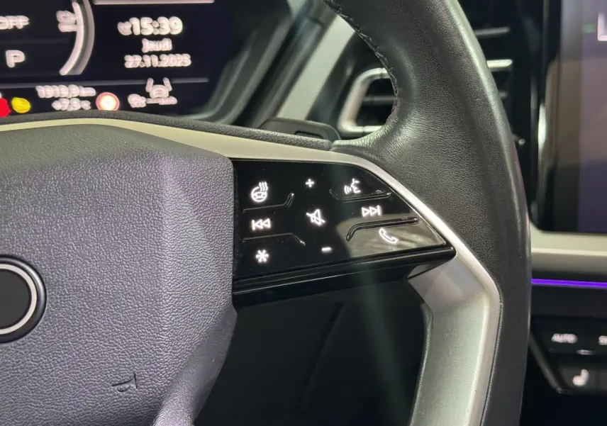 Gros plan sur le volant noir de l'Audi Q4 E-TRON 2022 avec commandes tactiles rétroéclairées côté droit.