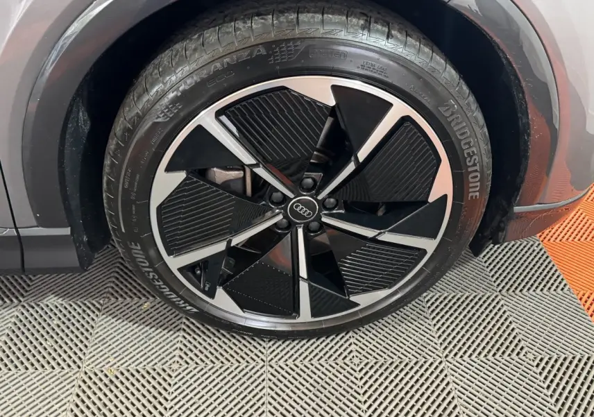 Gros plan sur la roue avant gauche gris foncé de l'Audi Q4 E-TRON 50 quattro avec jante noire et argentée design moderne.
