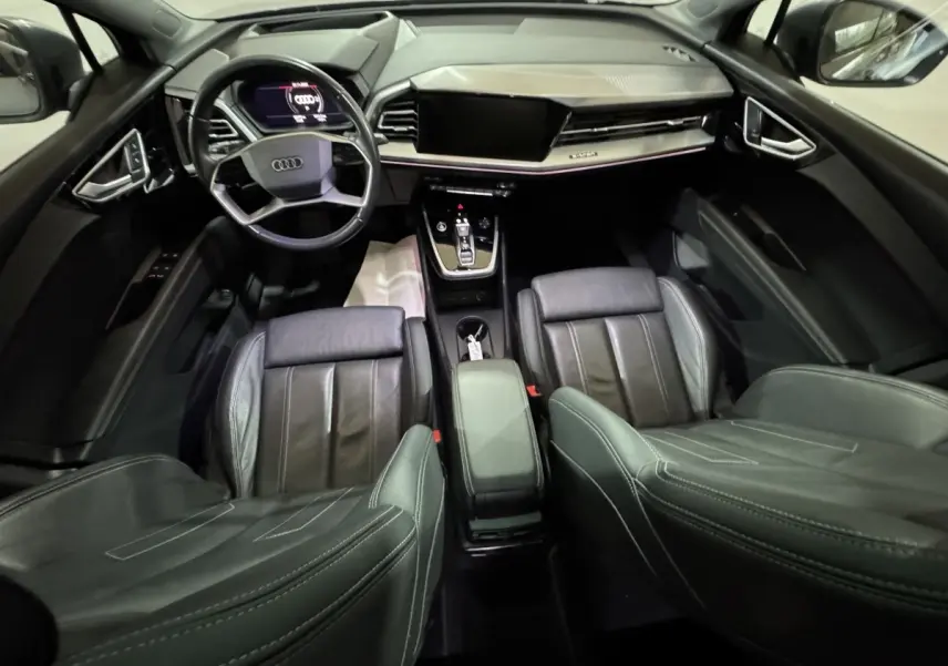 Vue intérieure de l'Audi Q4 E-TRON Design Luxe 2022, tableau de bord et sièges en cuir noir avec volant multifonctions.